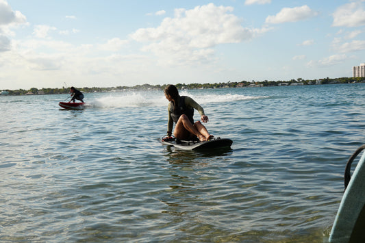 Beginner standing up and riding a Moovi electric surfboard on the calm flats of Biscayne Bay