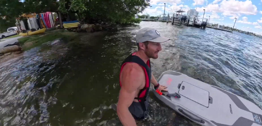 eFoil rider standing in shallow water in Miami, holding a Waydoo board set up with the 19.5 inch short mast near the shoreline.