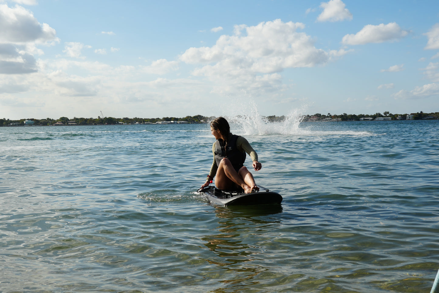 Beginner riding a Moovi electric surfboard with water spray